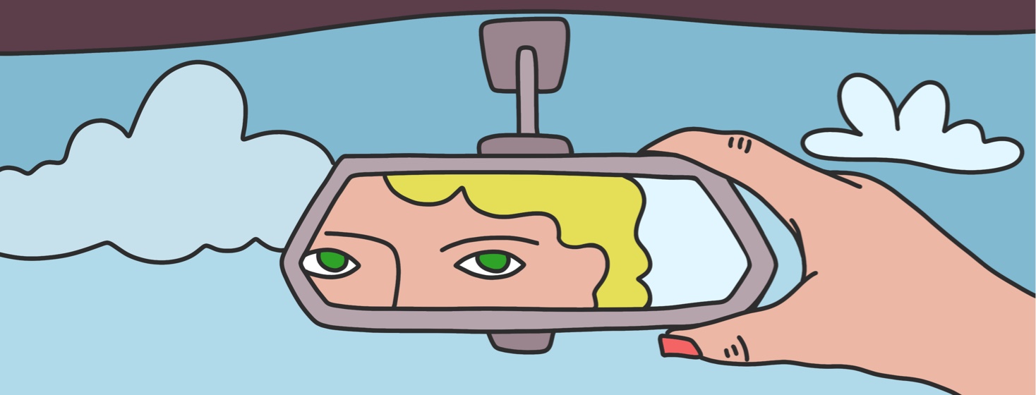 A person with green eyes looking in their reflection in the rearview mirror of a car.