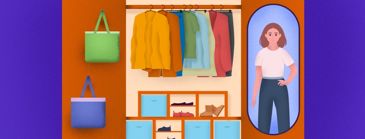 A woman looks at her reflection in the mirror next to her color coordinated closet.